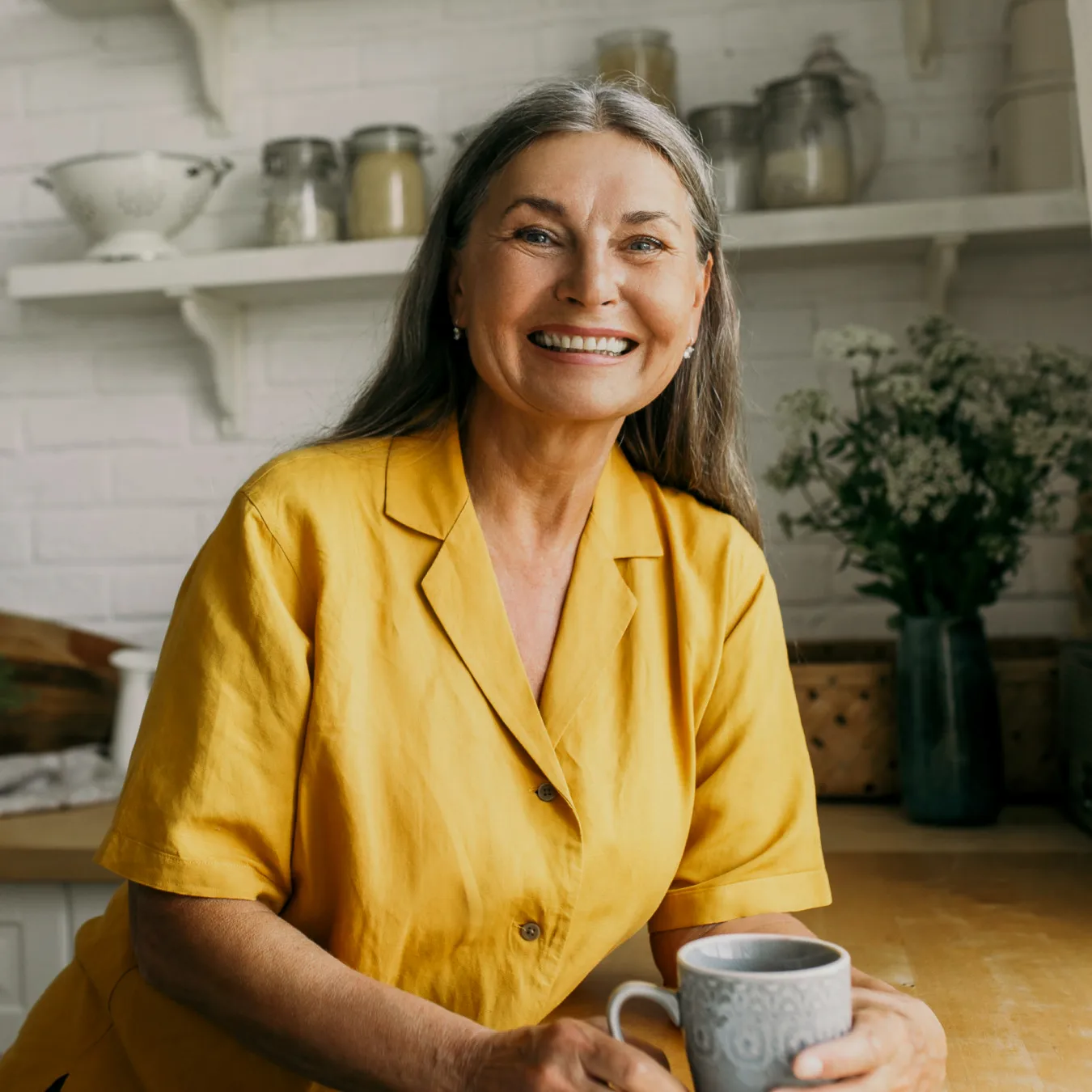 senior woman smiling in her kitchen drinking coffee