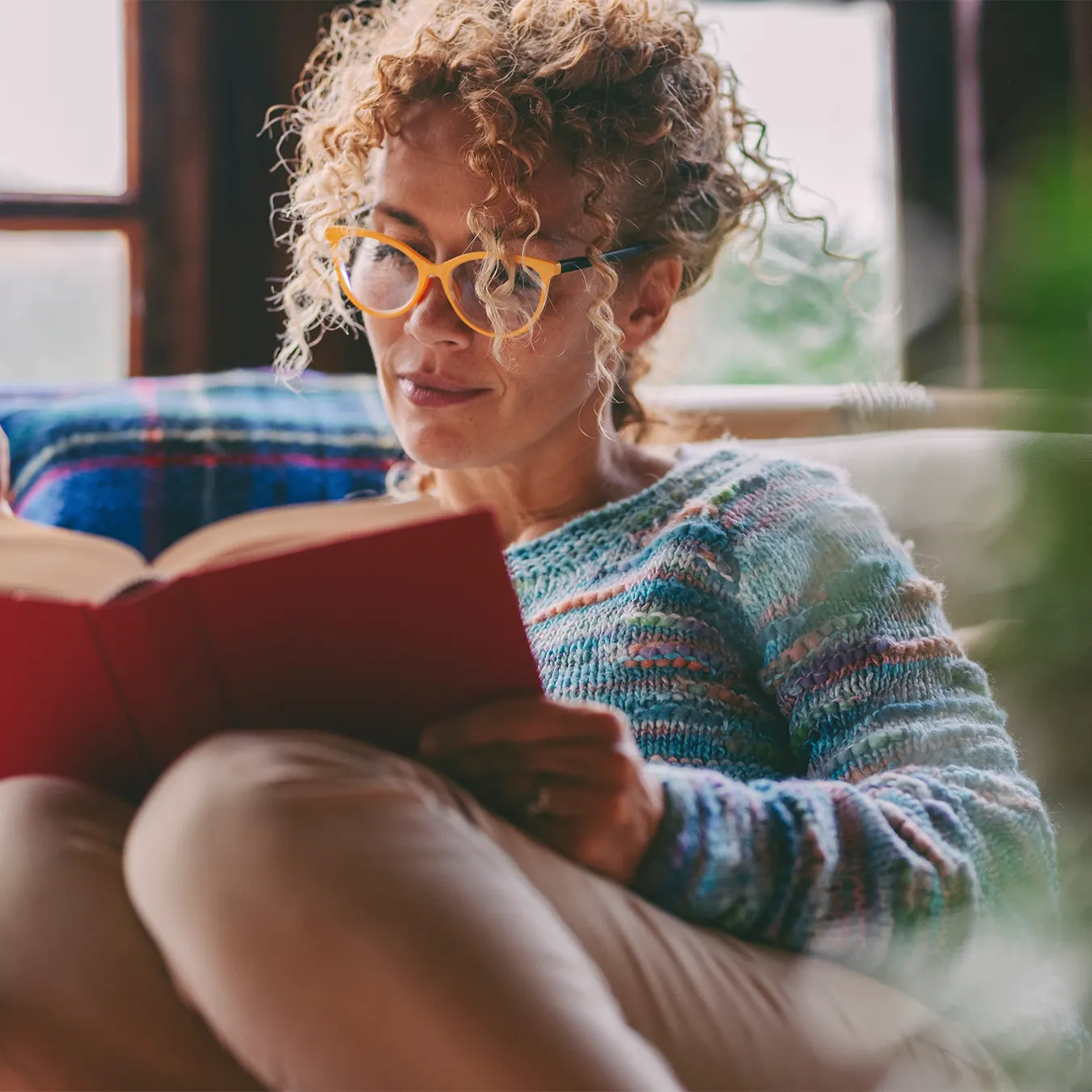woman in her 40's wearing glasses and reading a book
