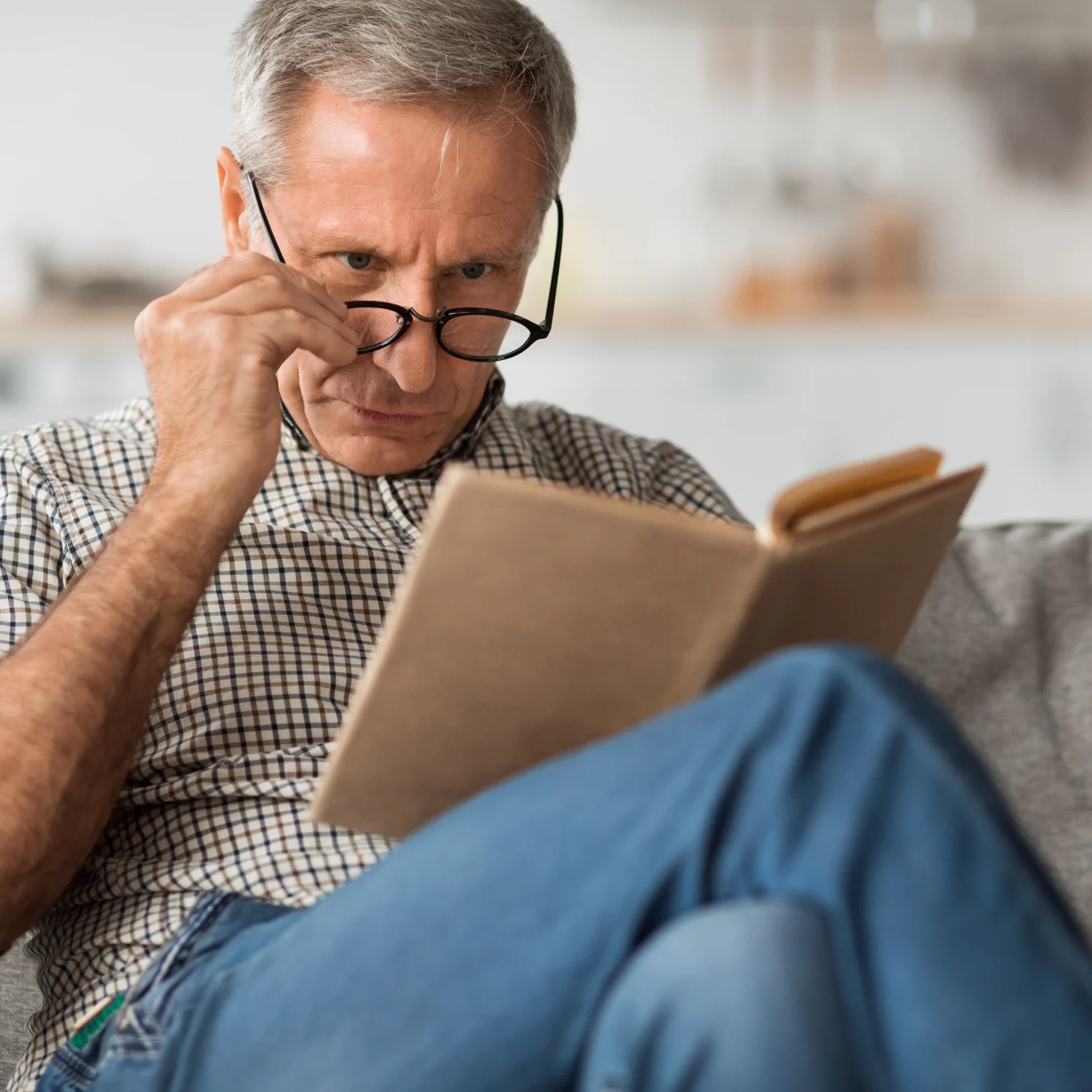 man 50s having trouble reading a book with his reading glasses