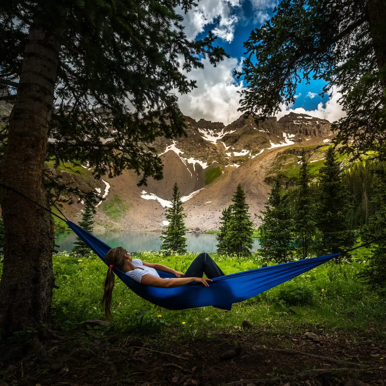 person lying in hammock looking at the mountain view